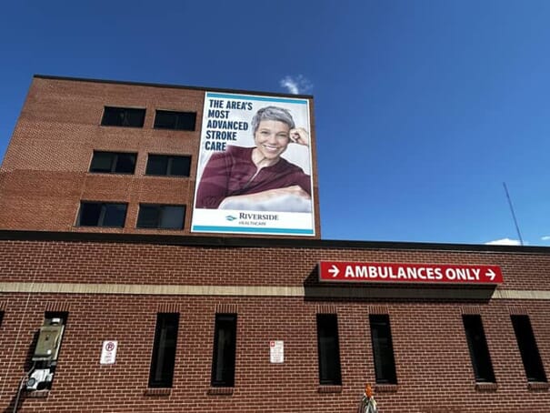 An image of an "advanced stroke care" outdoor poster on the side of a hospital above the ambulance bay.
